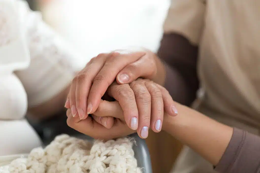 Caregiver holding hands with patient