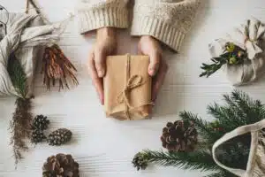 Sustainable gift giving with hands showing an eco-wrapped gift surrounded by fir leaves