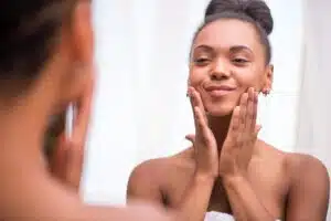 Beautiful Black woman admires her skin in the mirror