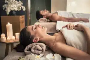 Young man and woman lying down on massage beds at luxury spa illustrating industry rebound and wellness center