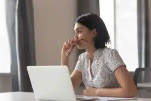 Thoughtful Asian woman looks anxious and stressed sitting in front of her laptop
