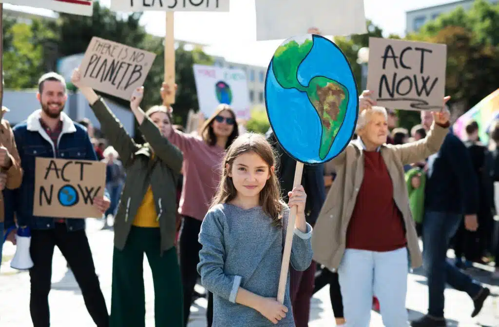A young girl holding a sign representing the planet and others protesting on strike for climate change