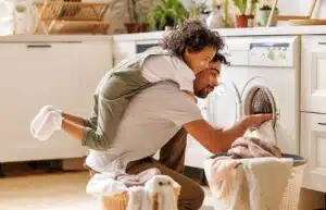 A dad with his son on his back does the laundry