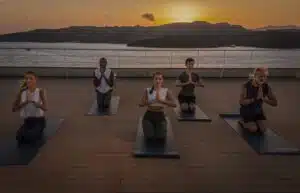 Several people doing yoga on a ship at sunset