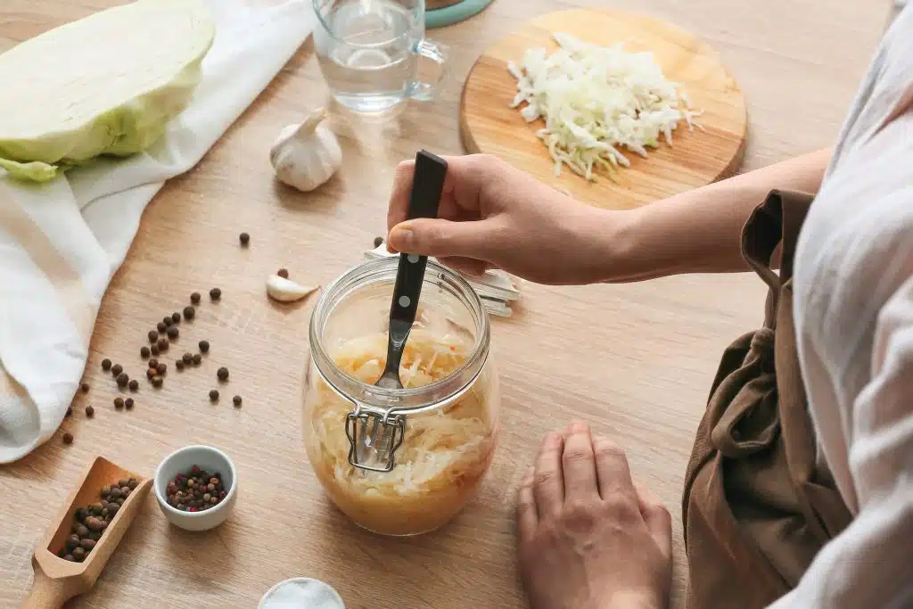A woman preparing sauerkraut, which is good for gut health.
