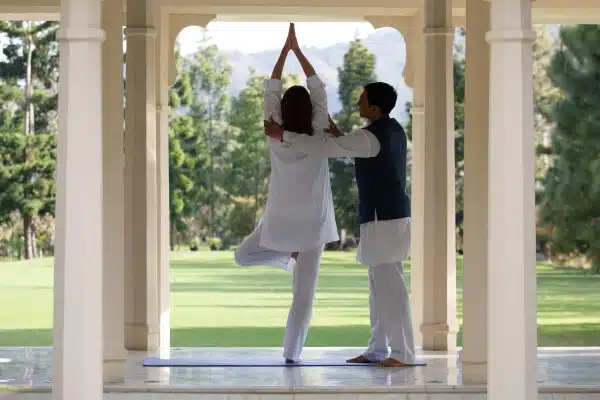 A guest practices tree pose with the help of an instructor at Ananda in the Himalayas