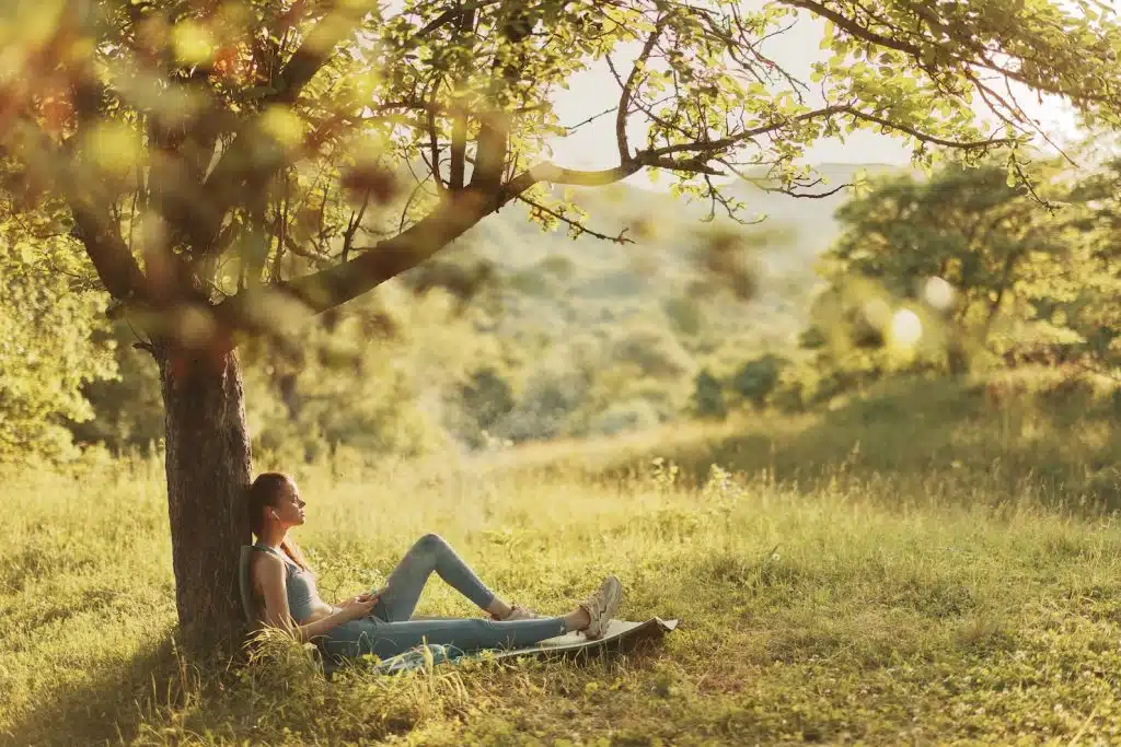 A woman in workout gear lies beneath a tree finding solace