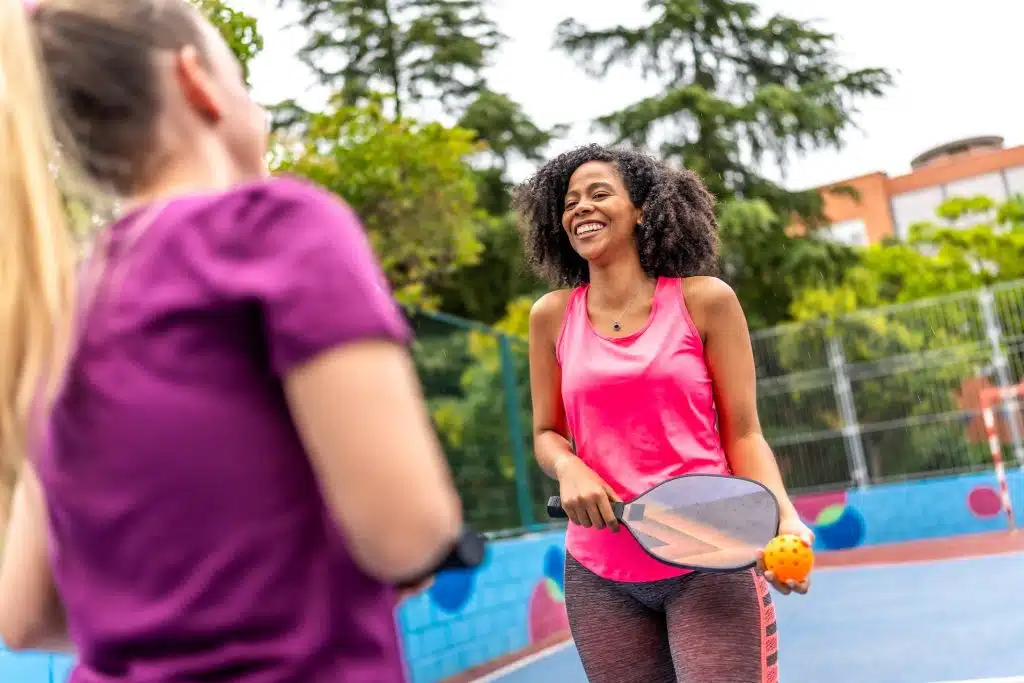 Two women converse on a pickleball court