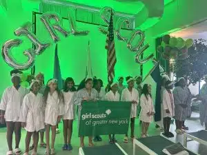 Girl Scouts from Queens pose in front of a Girl Scouts sign at Spa Castle
