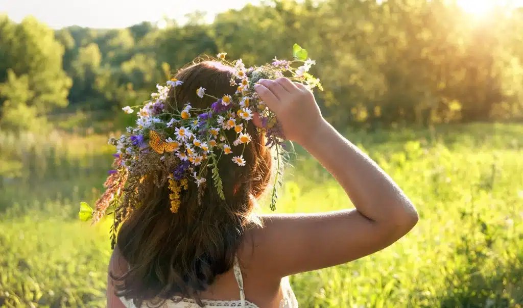 A girl looks out over a field while wearing a flower crown...meant to depict Midsummer.