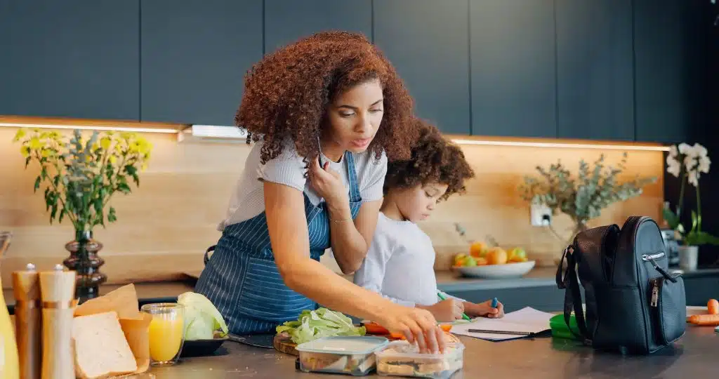 Woman makes lunch for her child in the kitchen while on the phone.