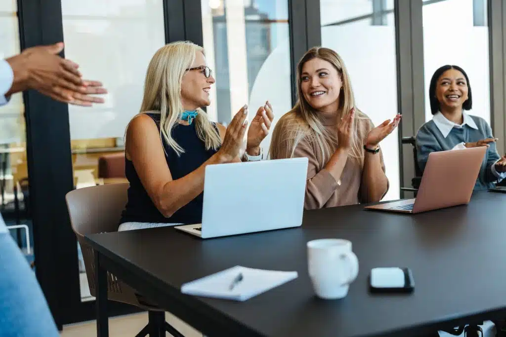 Two women at work, one in front of a laptop, celebrating their success.