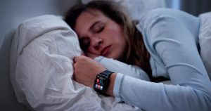 A woman asleep while her smart watch tracks her heart rate.