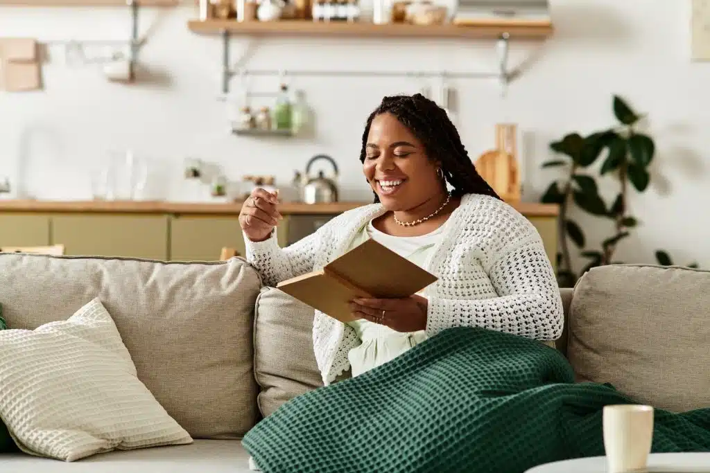 Young woman enjoys a peaceful morning reading while wrapped in a soft blanket at home.