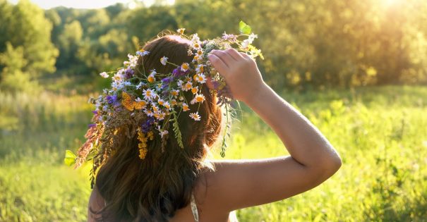 A girl looks out over a field while wearing a flower crown...meant to depict Midsummer.